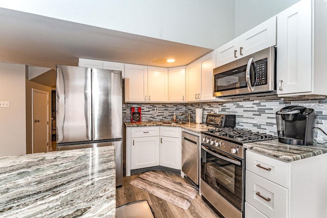 kitchen with light stone countertops, white cabinets, and stainless steel appliances