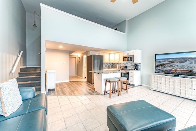 tiled living room with ceiling fan and a towering ceiling