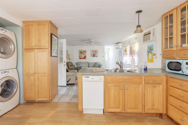 kitchen featuring stacked washing maching and dryer, dishwasher, sink, hanging light fixtures, and light brown cabinets