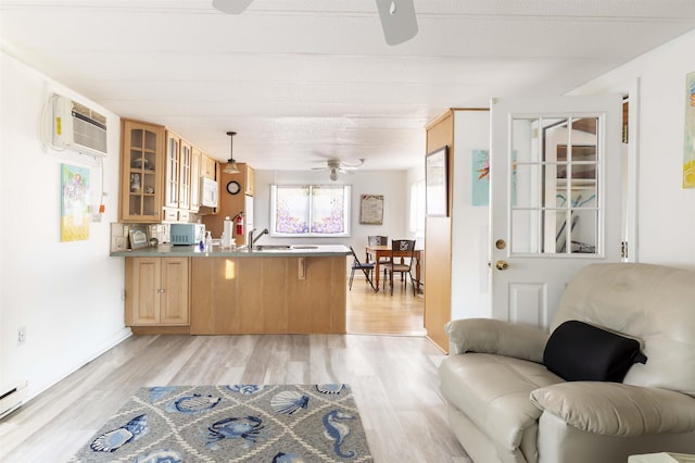 kitchen with hanging light fixtures, light wood-type flooring, an AC wall unit, kitchen peninsula, and ceiling fan