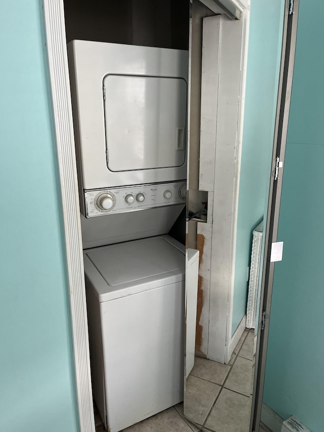 clothes washing area with light tile patterned floors and stacked washer and clothes dryer