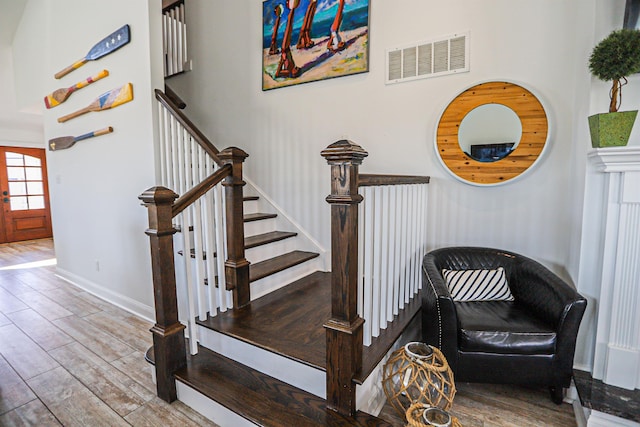 stairway with visible vents, baseboards, and wood finished floors