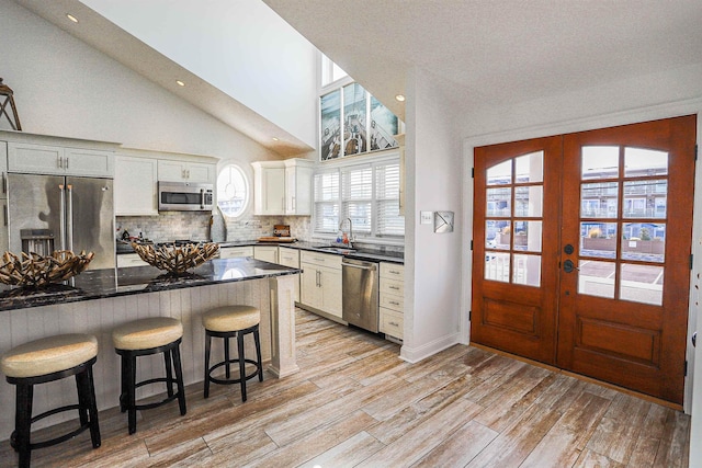 kitchen with appliances with stainless steel finishes, light wood-type flooring, french doors, and white cabinetry