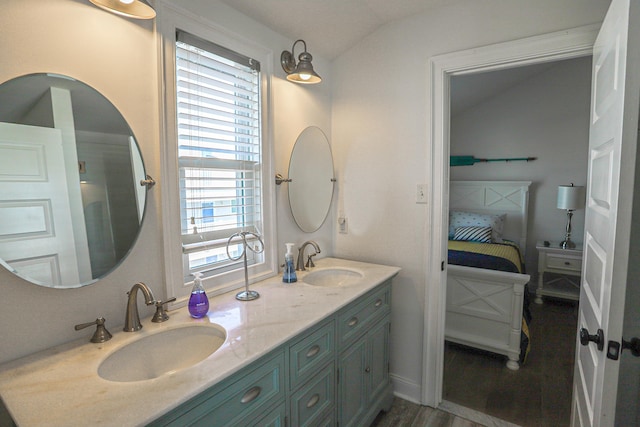 bathroom featuring wood finished floors, vaulted ceiling, a sink, and double vanity