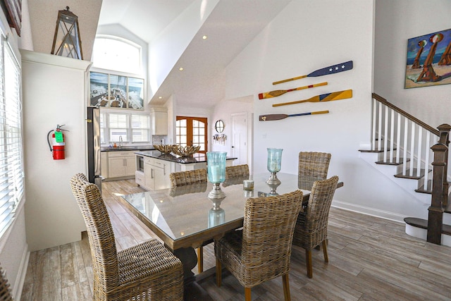 dining area with baseboards, wood finished floors, stairs, high vaulted ceiling, and recessed lighting