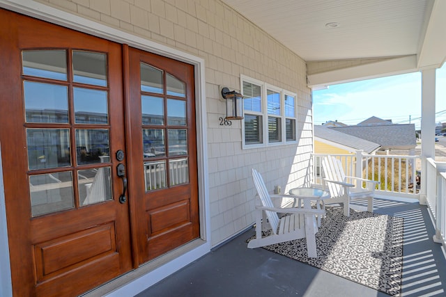 doorway to property featuring covered porch and french doors