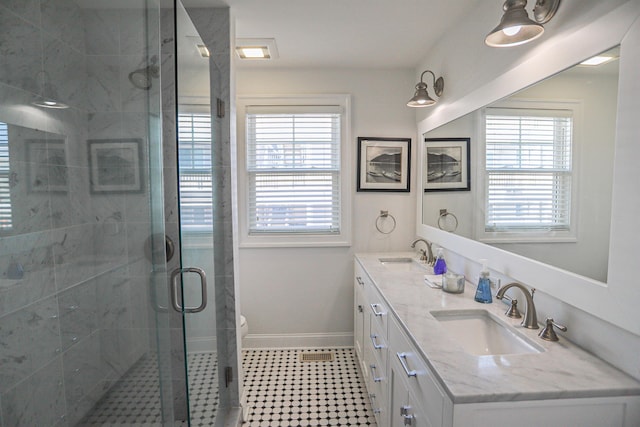 full bath featuring a stall shower, a sink, baseboards, and double vanity