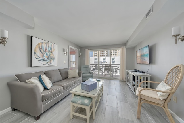 living room featuring wood tiled floor, baseboards, and visible vents