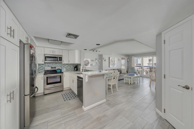 kitchen featuring open floor plan, light countertops, a peninsula, appliances with stainless steel finishes, and visible vents