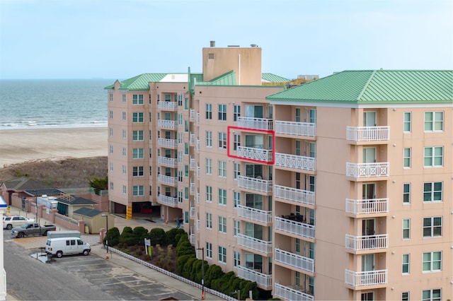 view of property featuring uncovered parking, a beach view, and a water view