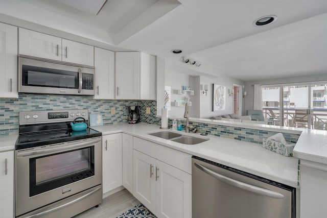 kitchen featuring light countertops, backsplash, a sink, appliances with stainless steel finishes, and open floor plan