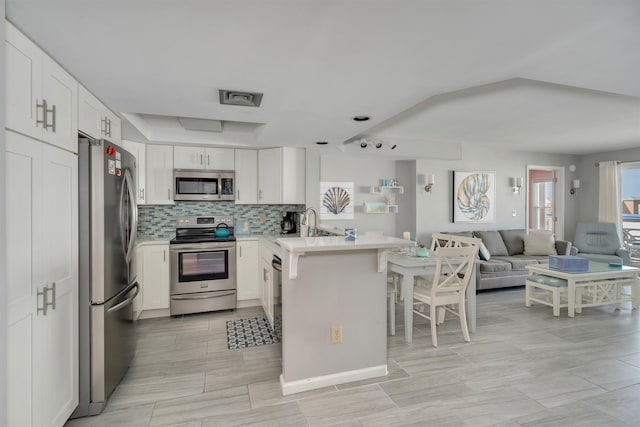 kitchen with light countertops, visible vents, a peninsula, appliances with stainless steel finishes, and open floor plan