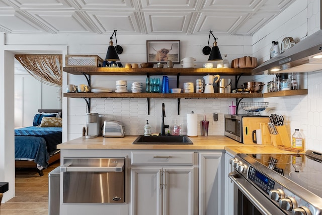 bar with sink, appliances with stainless steel finishes, and wooden counters