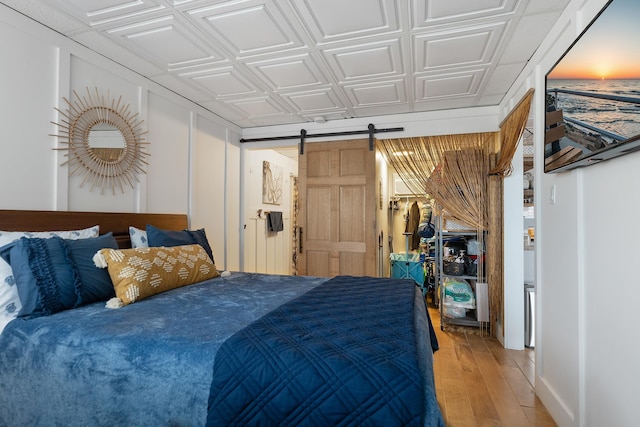 bedroom featuring wood-type flooring and a barn door