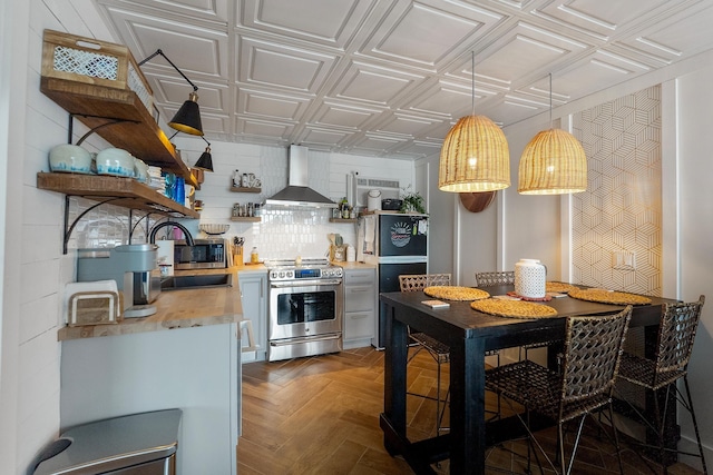 kitchen featuring sink, dark parquet floors, wall chimney range hood, and stainless steel appliances