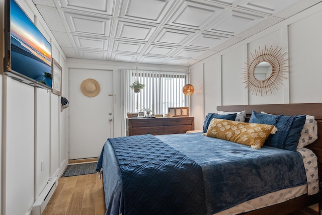 bedroom with a baseboard radiator and light hardwood / wood-style floors