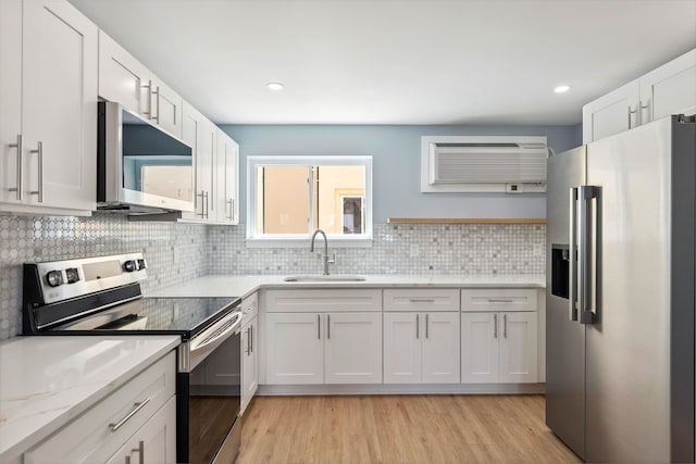 401 Ocean Ave Unit 202, North Wildwood, NJ 08251 - kitchen featuring stainless steel appliances, a sink, a wall unit AC, tasteful backsplash, and white cabinetry
