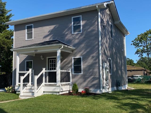 back of property featuring covered porch and a yard