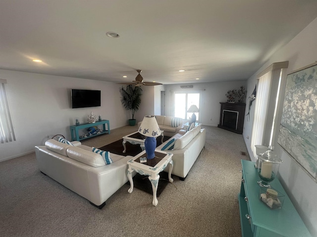 carpeted living room with ceiling fan and a fireplace