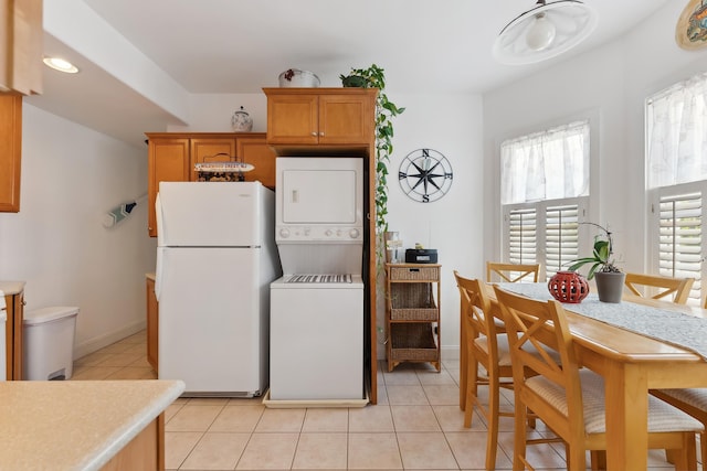 kitchen featuring white refrigerator, light tile patterned floors, and stacked washer and clothes dryer