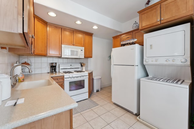 kitchen featuring sink, tasteful backsplash, stacked washer / dryer, white appliances, and light tile patterned floors