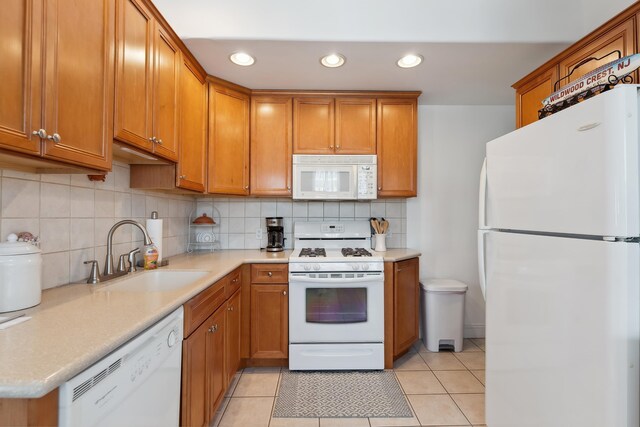 kitchen with decorative backsplash, light tile patterned floors, white appliances, and sink