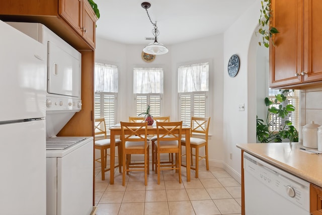 tiled dining room with stacked washer / drying machine