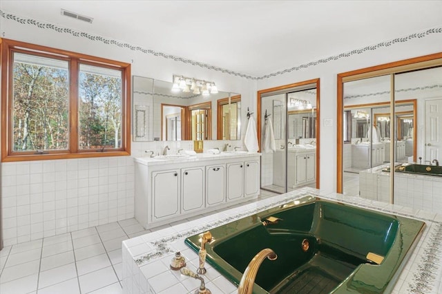 full bath featuring double vanity, tile walls, visible vents, and a sink