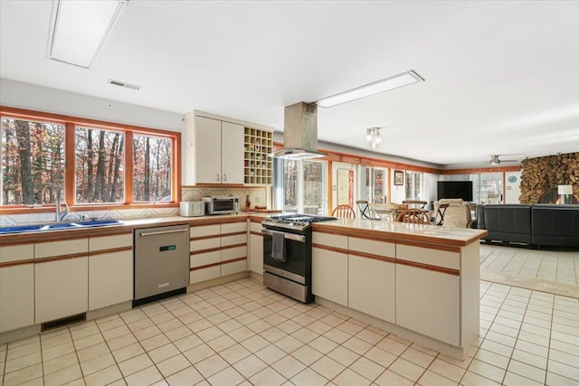 kitchen featuring island exhaust hood, visible vents, appliances with stainless steel finishes, open floor plan, and a peninsula