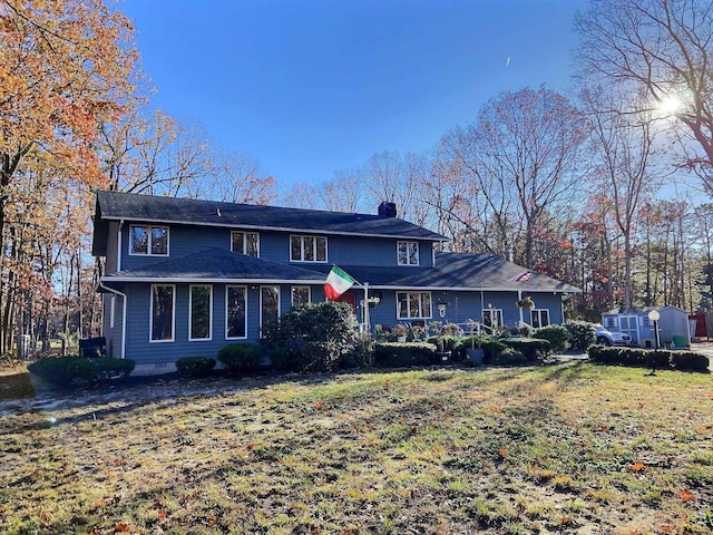 view of front of home with a front yard and a shed