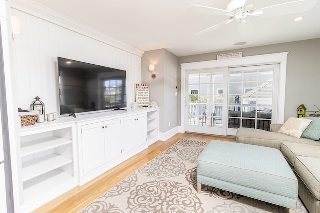 living area featuring light wood finished floors, ceiling fan, baseboards, and ornamental molding