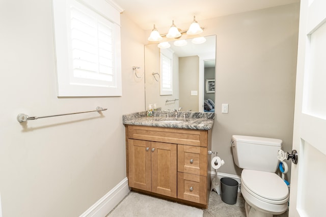 half bathroom featuring tile patterned flooring, baseboards, vanity, and toilet