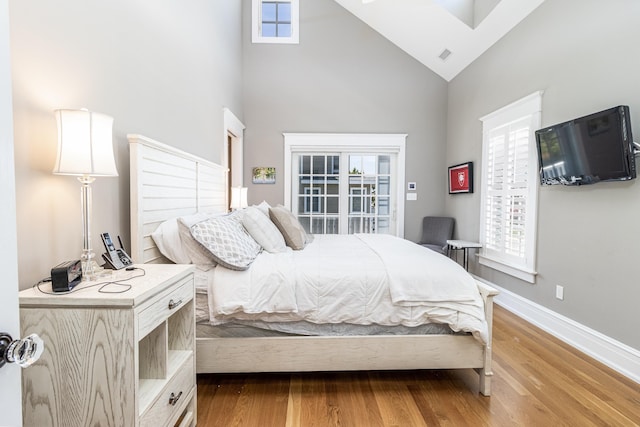 bedroom featuring high vaulted ceiling, visible vents, baseboards, and wood finished floors