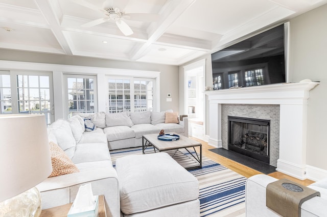 living room with light wood-style floors, coffered ceiling, beamed ceiling, and a tile fireplace