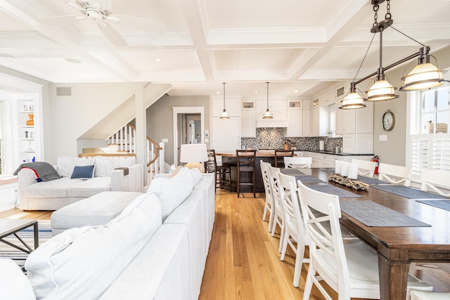 living area featuring ceiling fan, light wood-style flooring, coffered ceiling, and visible vents