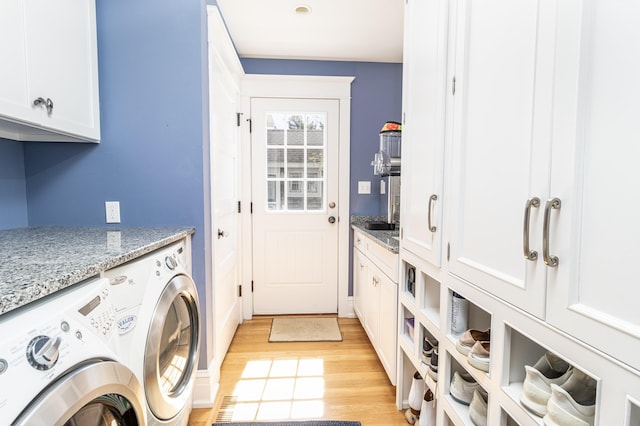 laundry room featuring light wood-type flooring, cabinet space, and washer and dryer