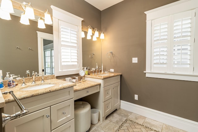 full bathroom featuring two vanities, a sink, and baseboards