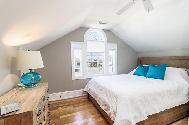 bedroom featuring baseboards, visible vents, a ceiling fan, lofted ceiling, and wood finished floors