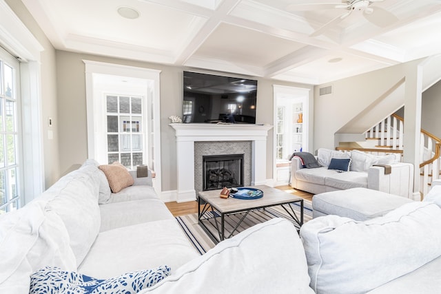 living area with visible vents, stairway, wood finished floors, a fireplace, and beam ceiling