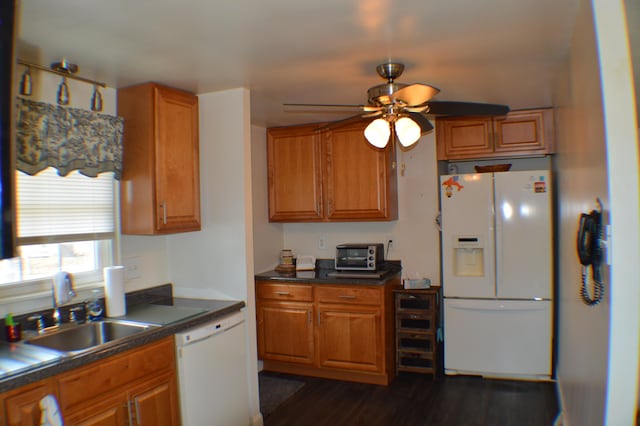 kitchen featuring white appliances, dark countertops, a sink, and brown cabinets