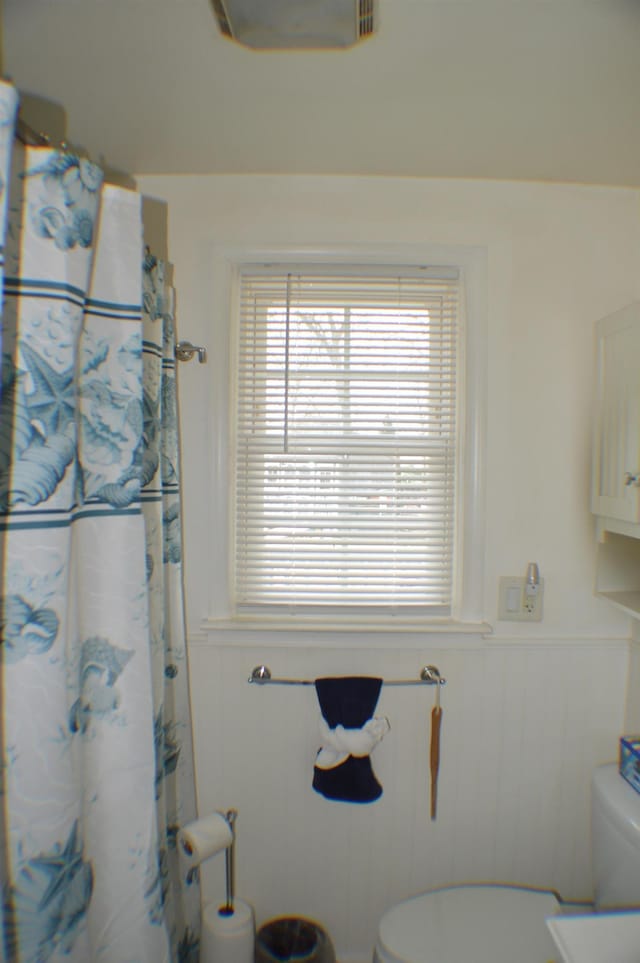 full bath featuring wainscoting and toilet