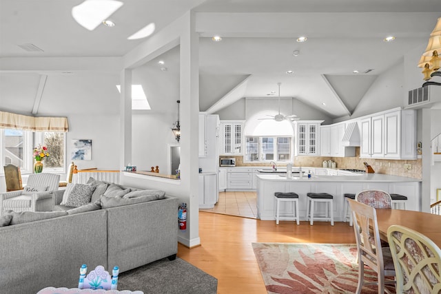 living area with visible vents, light wood-type flooring, a ceiling fan, and a healthy amount of sunlight