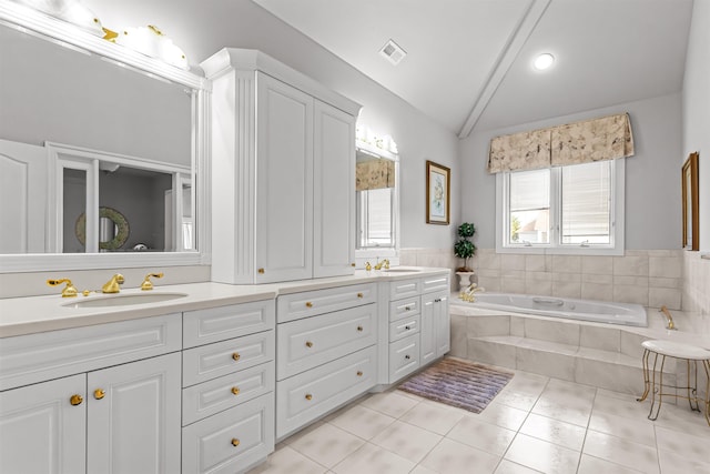full bathroom featuring a sink, double vanity, vaulted ceiling, tile patterned floors, and a garden tub