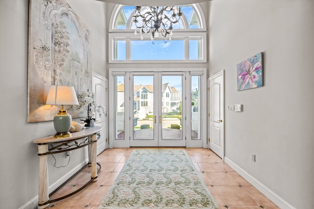 foyer entrance featuring a notable chandelier, baseboards, french doors, a high ceiling, and light tile patterned flooring