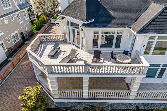 rear view of house featuring a shingled roof and stucco siding