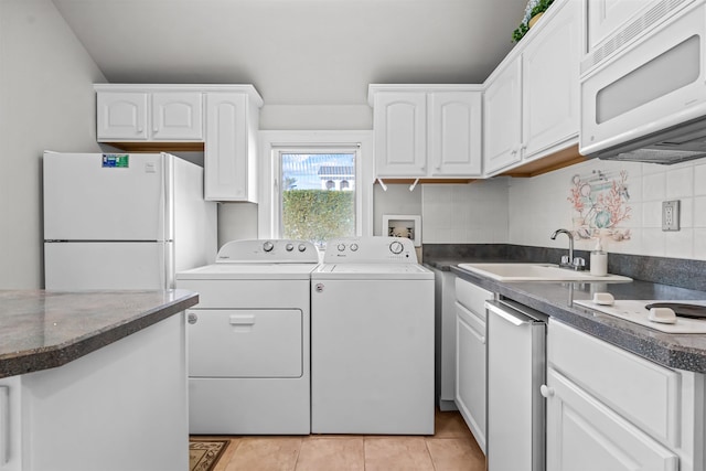 washroom with light tile patterned floors, separate washer and dryer, laundry area, and a sink