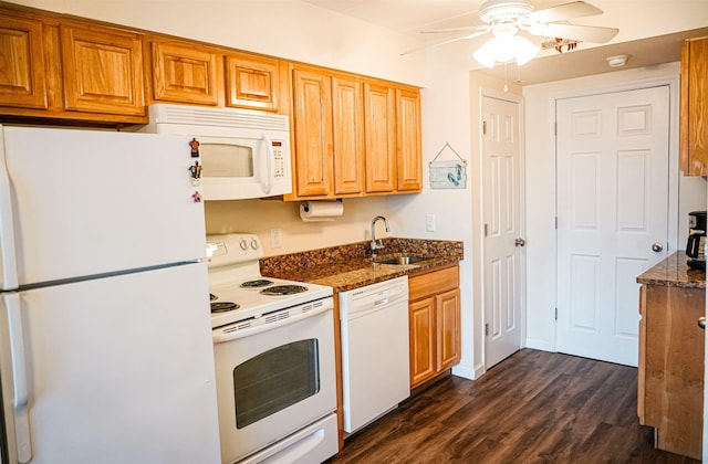 kitchen with dark wood-style flooring, a ceiling fan, a sink, dark stone counters, and white appliances