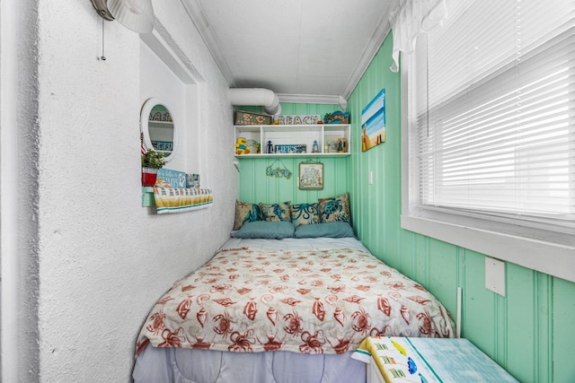 bedroom with ornamental molding and a textured wall