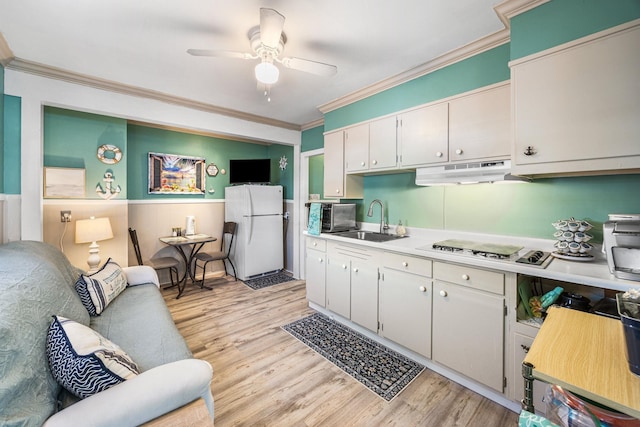 kitchen with freestanding refrigerator, under cabinet range hood, stovetop, a sink, and ornamental molding