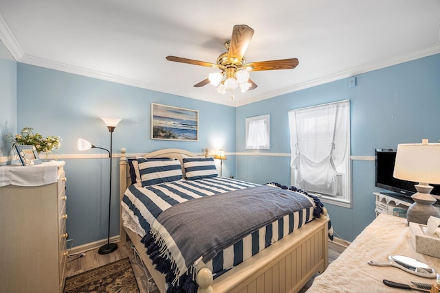 bedroom featuring wood finished floors, crown molding, a wainscoted wall, and a ceiling fan